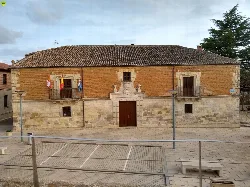 Edificio del ayuntamiento con fachada de piedra y banderas en el balcón.