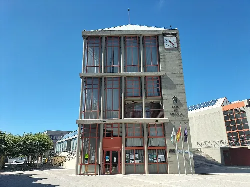 Mehrstöckiges Gebäude mit Uhr und Flaggen an der Fassade in Xove.