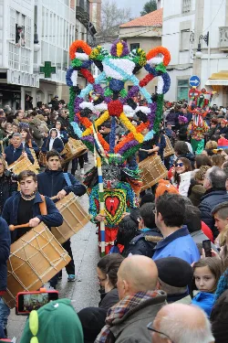 Karnevalsumzug mit großer geschmückter Figur und Trommlern auf der Straße.