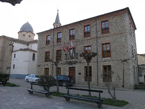 Rathaus in Ruiloba mit der Pfarrkirche der Himmelfahrt im Hintergrund.
