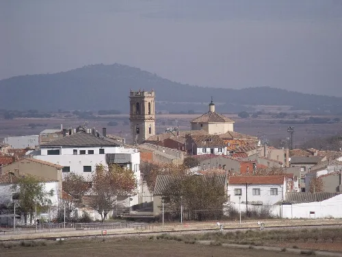 Blick auf eine Stadt mit Kirche und Hügeln im Hintergrund.