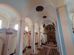View of the interior of a church with arches, columns, and benches.