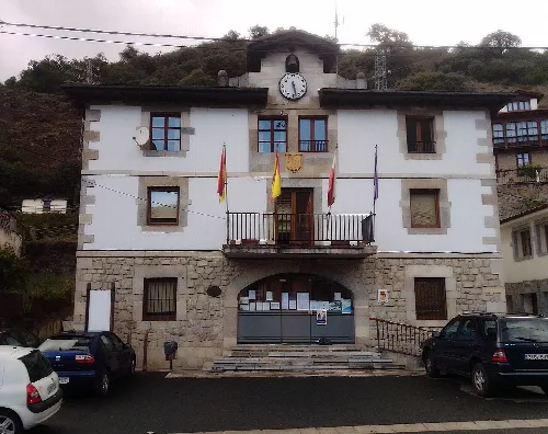 Edificio con reloj y banderas en La Vega de Liébana.