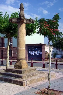 Steinkreuz in Huércanes, La Rioja, mit Bäumen und Aushang.