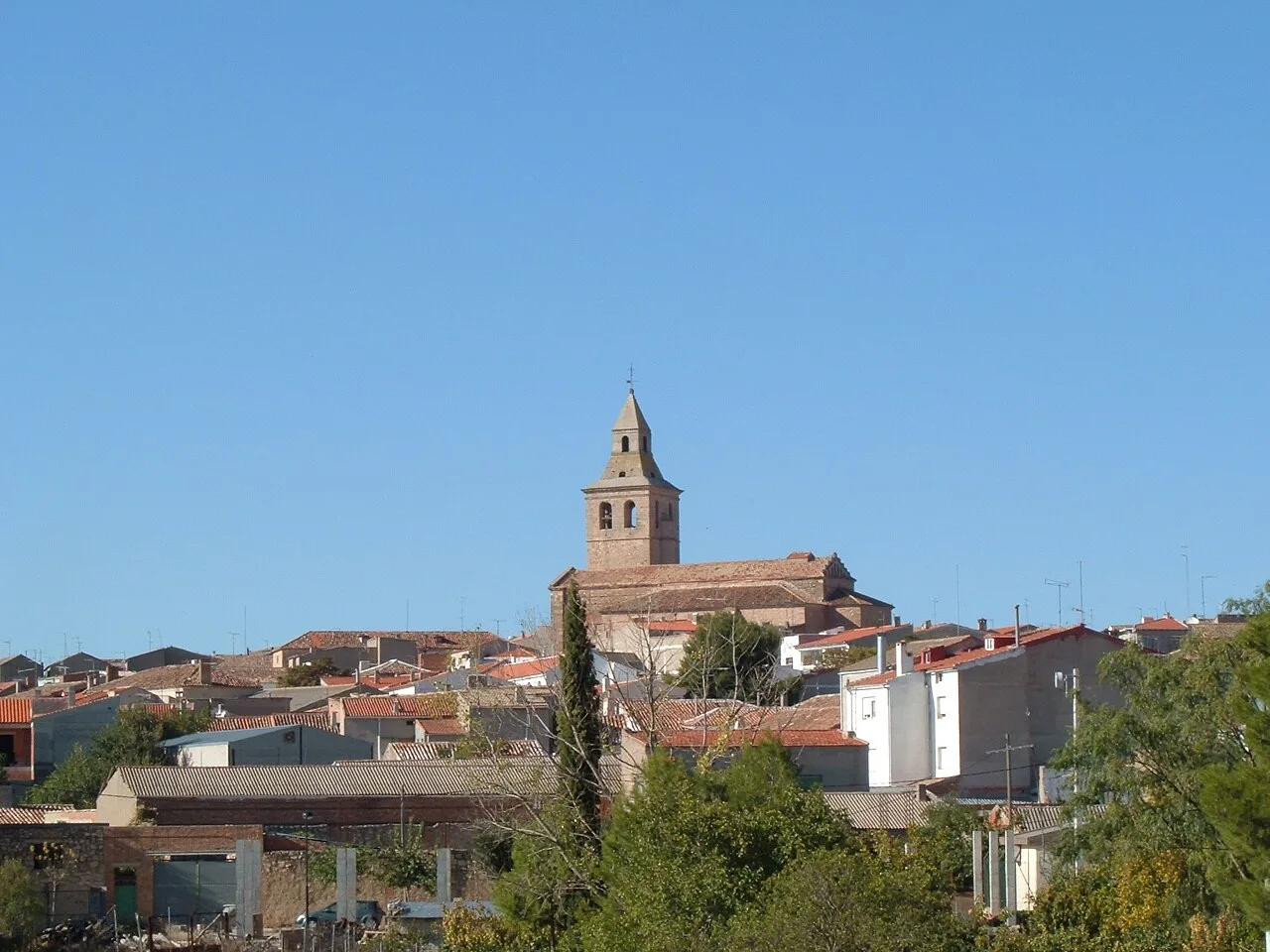 Blick auf eine Stadt mit Kirche und Dächern im Herbst unter blauem Himmel.