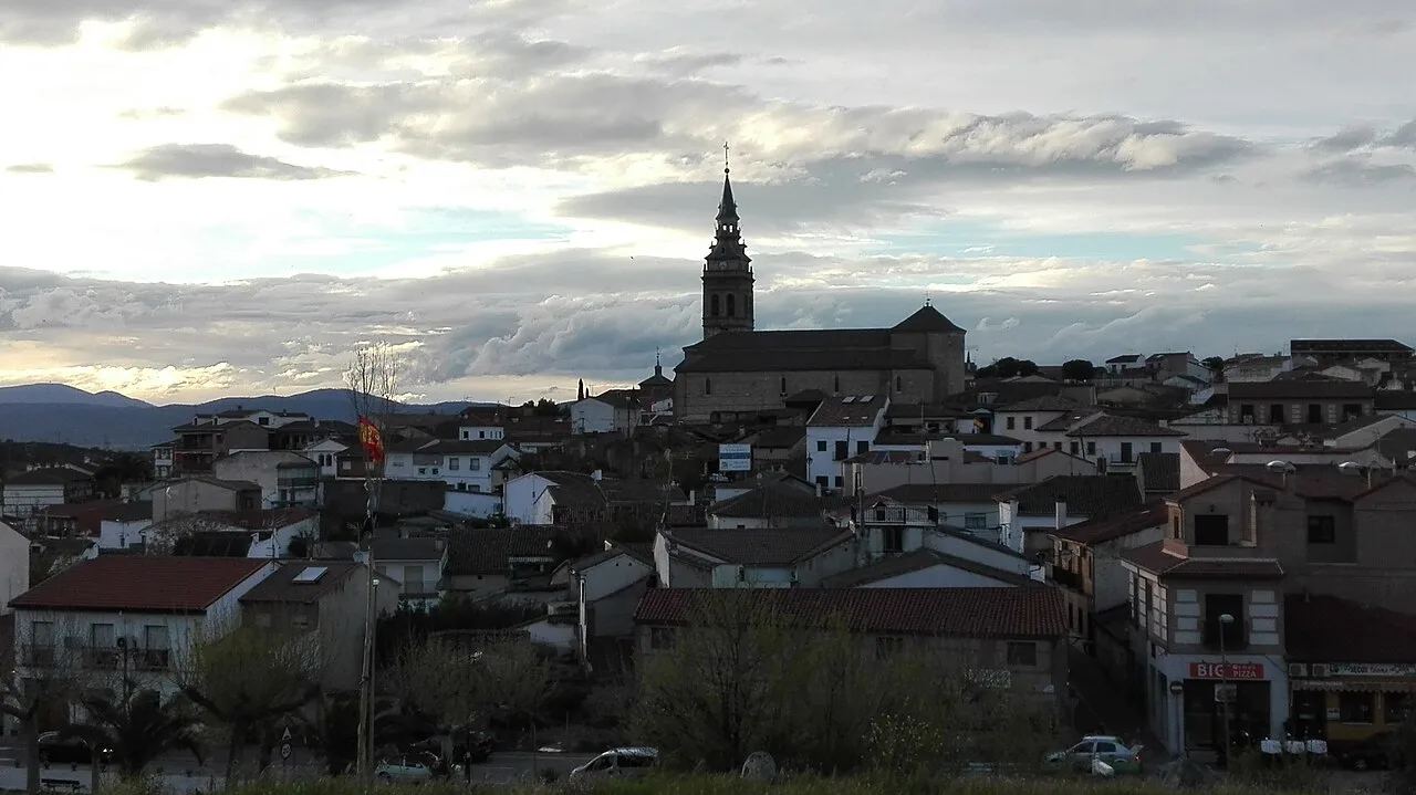 Blick auf die Stadt mit Kirche und Häusern unter bewölktem Himmel.