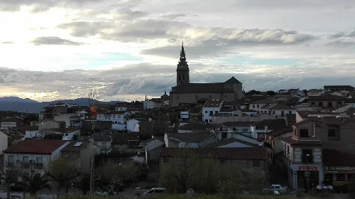 View of the town with church and houses under a cloudy sky.