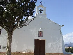 Weiße Fassade einer kleinen Hermitage mit Glockenturm und Kreuz oben.