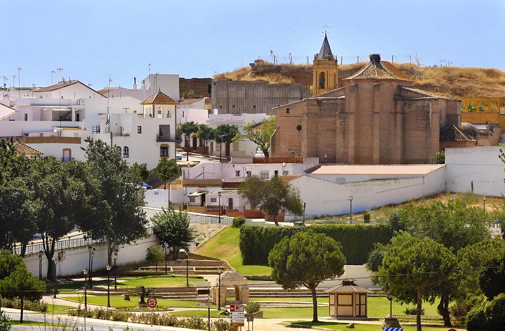 White houses, trees, and a church on the hill in Palos de la Frontera.