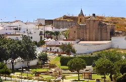 Casas blancas, árboles y iglesia en la colina en Palos de la Frontera.