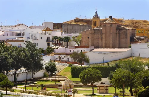 Weiße Häuser, Bäume und eine Kirche auf dem Hügel in Palos de la Frontera.
