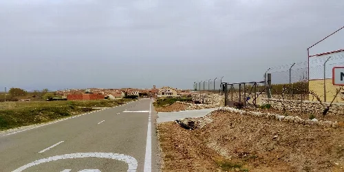 Rural road leading to Muñoveros with village in the background.