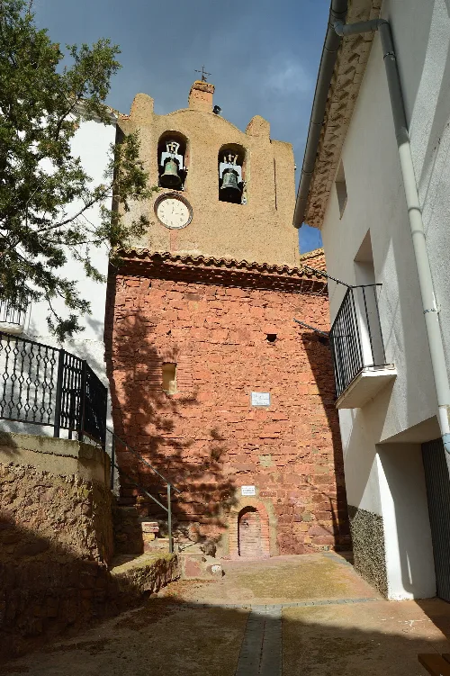 Brick church tower with bell openings, clock, and walls in Oseja.