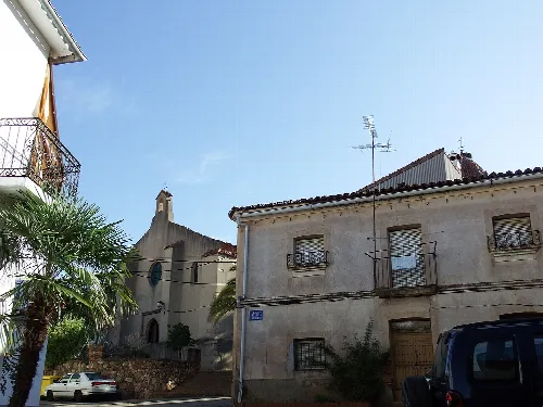 Häuser und Palmen in Cañamero, mit sichtbarer Kirche im Hintergrund.