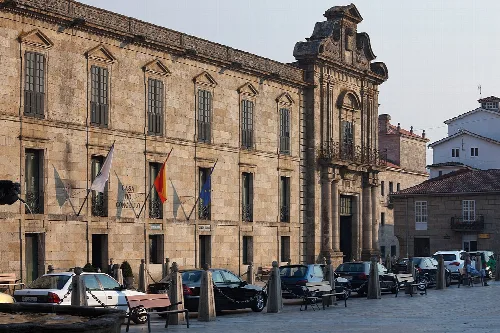 Gebäude des Rathauses von Celanova mit Flaggen und Bänken auf dem Platz.