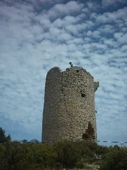 Stone cylindrical tower in Alcalá de Chivert with cloudy sky.