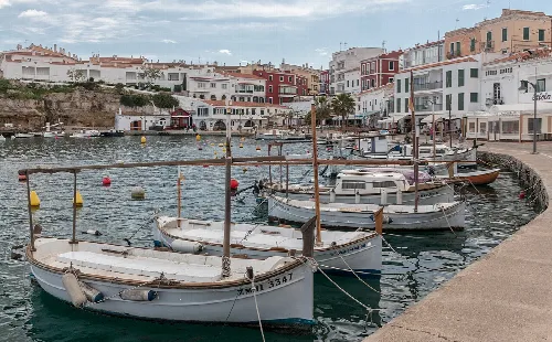 Boats docked in a harbor with buildings in Villacarlos.