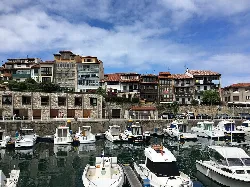 Barcos en el puerto de Llanes con edificios en el fondo.