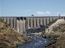 Large concrete dam in Cáceres, Extremadura, with river in foreground.