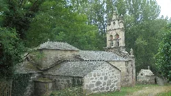 Iglesia de piedra con campanario en un entorno boscoso.