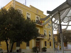 Benetússer town hall building with yellow facade and flags.