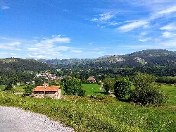 Paisaje con montañas, campos verdes y casas en Riotuerto.