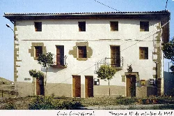 Weißes Gebäude mit Holzfenstern und Balkonen in Tirapu, Navarra.