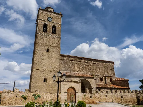 Steinerner Turm der befestigten Kirche der Himmelfahrt in Jabaloyas mit Glockenturm und Himmel.