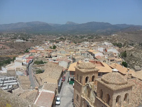 Blick auf Dächer und Straßen in Aledo, Murcia, mit Bergen am Horizont.