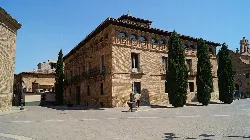 Brick building with tall trees in the square.