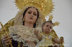 Estatua de la Virgen del Carmen con un niño en brazos, con detalles dorados y vestimenta elaborada.