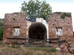 Ruins of an old chapel with brick walls and closed windows.