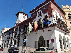 White building with clock and flags on the facade in Puente Genil