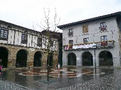 Edificio del ayuntamiento con arcos en la planta baja y fachada de piedra y madera.
