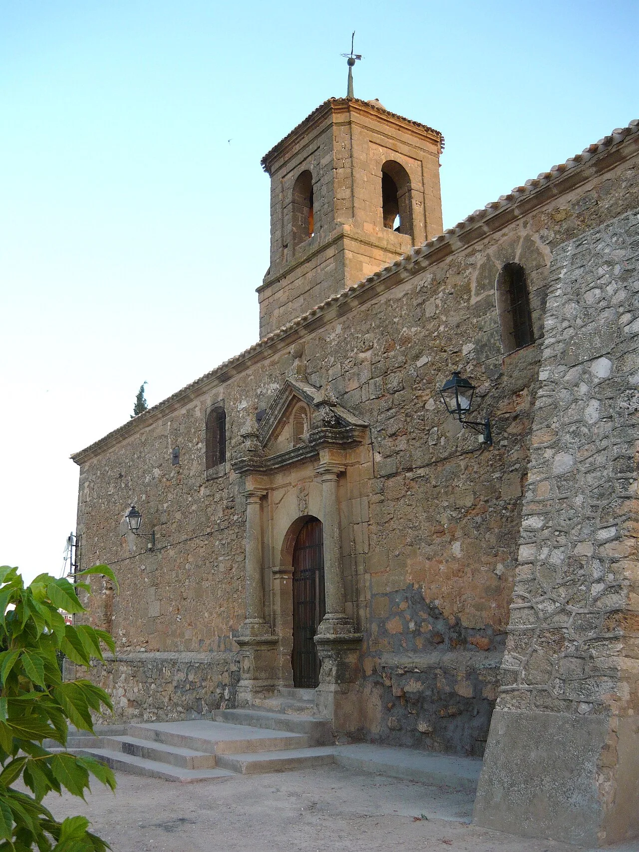 Iglesia de la Asunción en Olivares de Júcar, Cuenca, con campanario y fachada de piedra.
