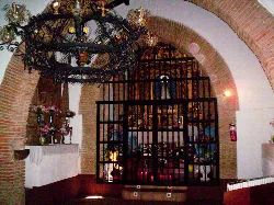 Innenansicht der Ermita mit Altar und schwarzem Gitter.