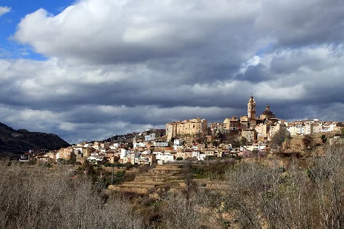 Panoramic view of Chelva with buildings and a church on the hill.
