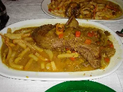 Dish of venison stew with fried potatoes on an oval plate.