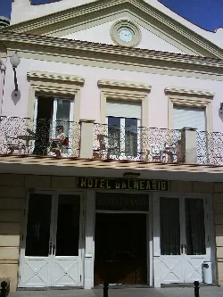 Hotel facade with balcony and person at a table