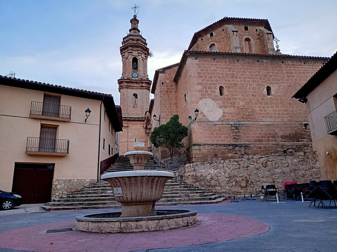 Plaza de España en Aguaviva con fuente y iglesia con torre.