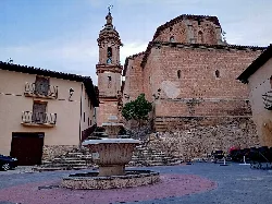Plaza de España en Aguaviva con fuente y iglesia con torre.