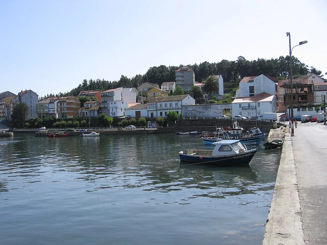 Blick auf den Hafen von Camariñas mit Häusern und Booten.
