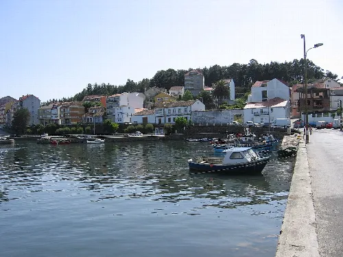 Blick auf den Hafen von Camariñas mit Häusern und Booten.