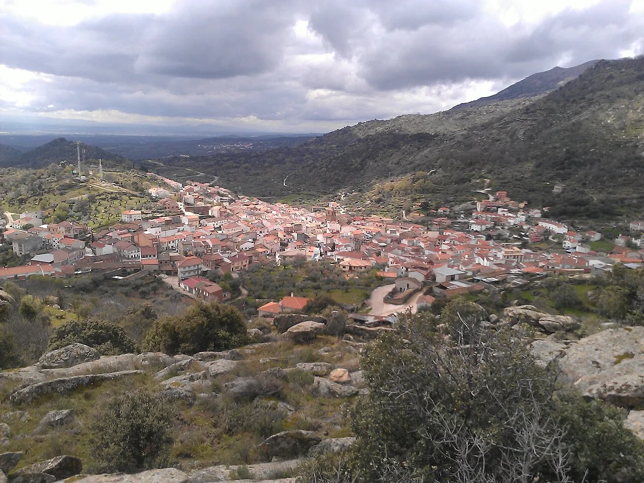 View of a town surrounded by mountains and vegetation.