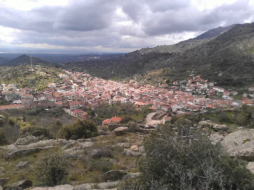 Blick auf eine Stadt umgeben von Bergen und Vegetation.