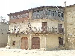 Edificio de piedra con balcones de hierro y ventanas de madera en San Felices de los Gallegos.