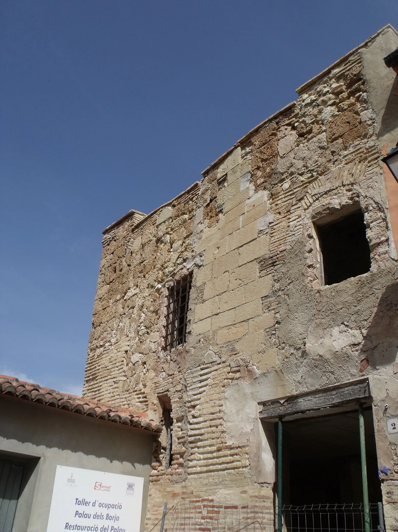 Restos de un edificio antiguo con muros de piedra y ventanas rotas en Castellón de Rugat.