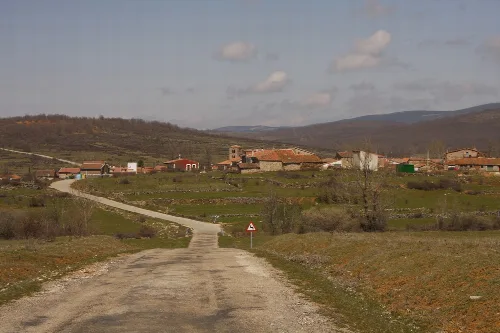 Rural road leading to a village with houses in Jaramillo de la Fuente, Burgos.