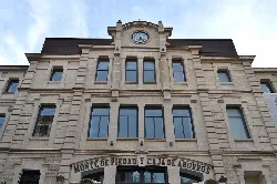 Facade of an old building with a clock and a sign that says 'Mont de Piedad and Savings Bank'.