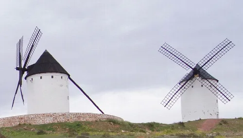 Zwei Windmühlen auf einer bewölkten Landschaft.